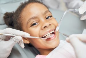 child in dental chair getting their teeth examined by dentist